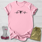 Pink t-shirt with a graphic gymnast heartbeat design, socks, and a drawstring bag on a light wooden surface.