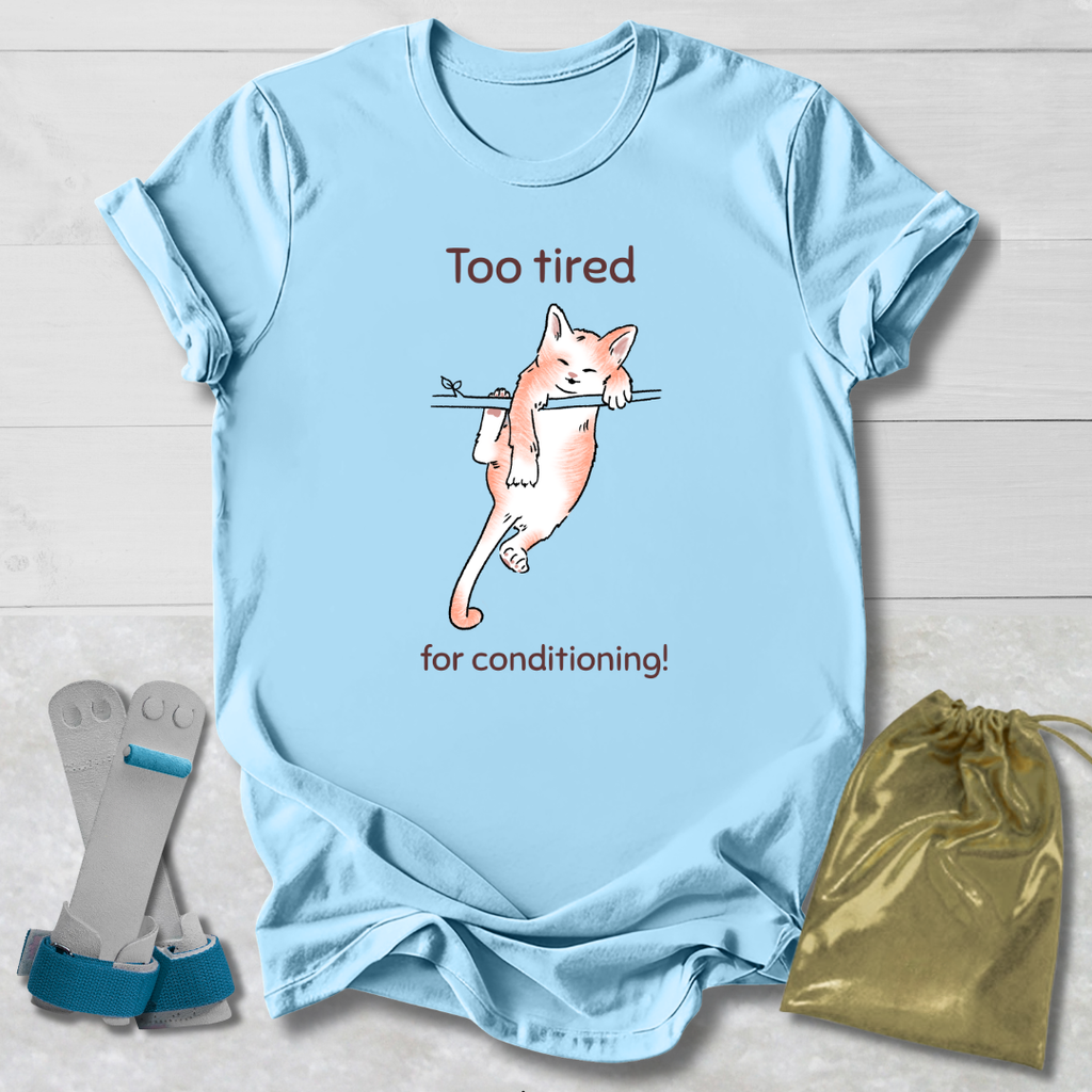 Light blue t-shirt with a cat that's too tired for gymnastics conditioning graphic and text, displayed with socks and a drawstring bag on a light wooden surface.