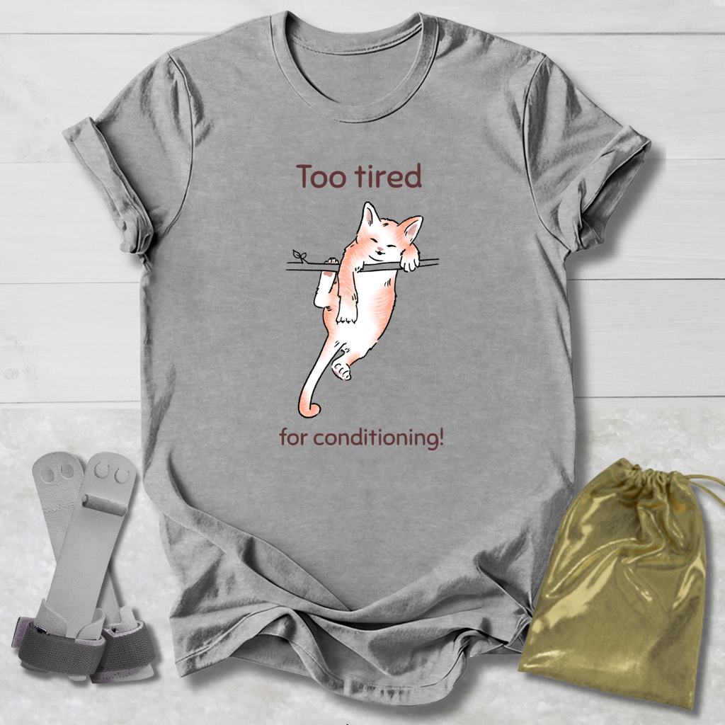 Gray t-shirt with a cat graphic and a cat that's too tired for gymnastics conditioning text, socks, and a drawstring bag on a wooden surface.