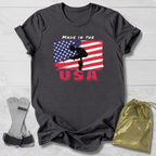 Gray t-shirt with Gymnast American flag graphic and 'Made in the USA' text on a wooden surface.