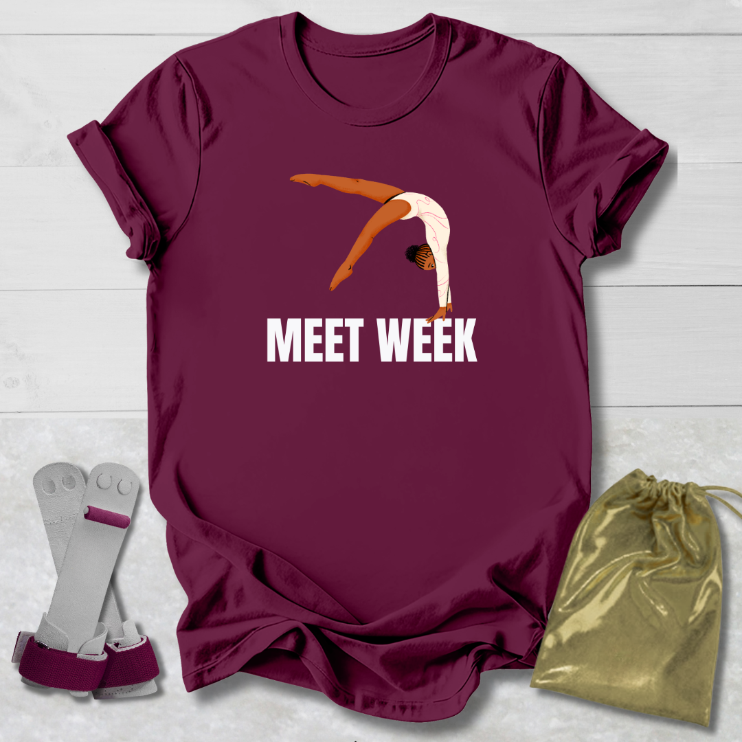 Maroon t-shirt with graphic and text, socks, and drawstring bag on a light wooden surface