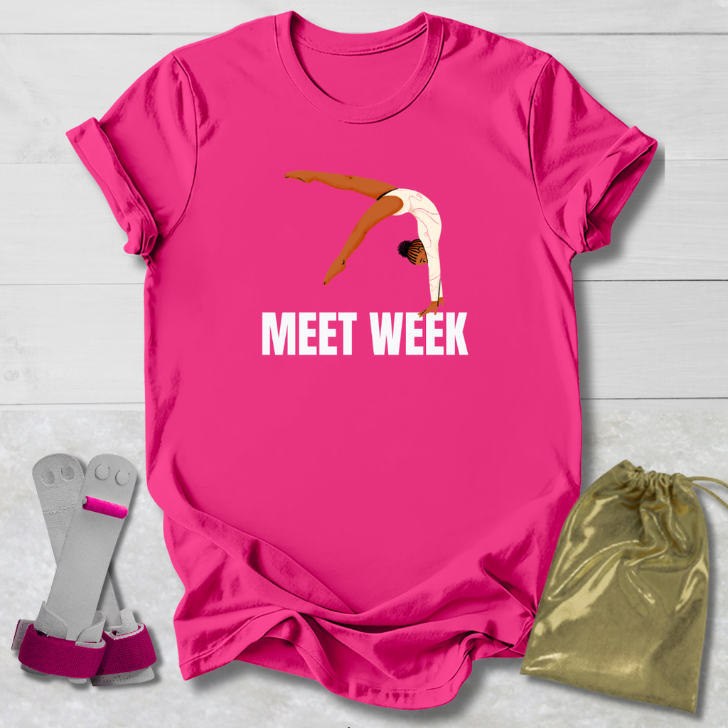 Pink t-shirt with a graphic and 'MEET WEEK' text, paired with socks and a drawstring bag on a light wooden surface.