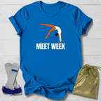 Blue t-shirt with a graphic and 'MEET WEEK' text, socks, and drawstring bag on a light wooden surface.