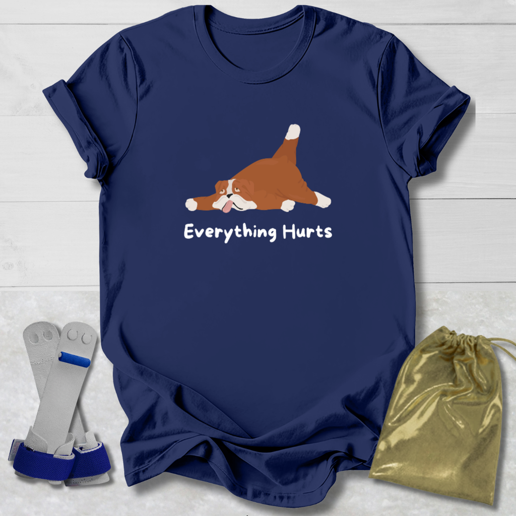 Navy blue t-shirt with a cartoon dog and 'Everything Hurts' text, displayed on a light wooden surface with socks and a drawstring bag.