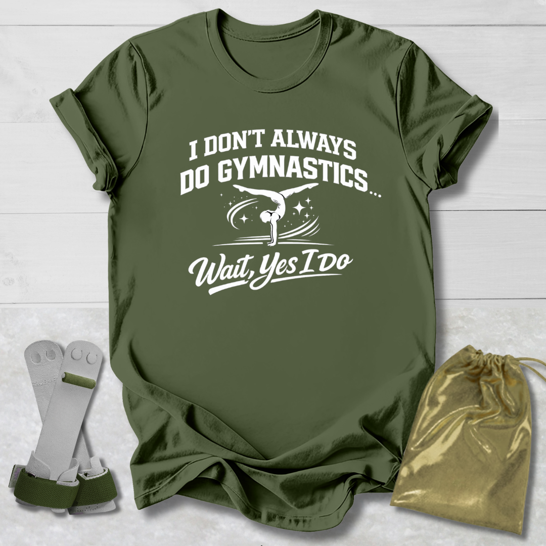 Green t-shirt with white I don't always do gymnastics . . . wait, yes I do text and graphics on a light wooden surface, accompanied by gray socks and a gold drawstring bag.