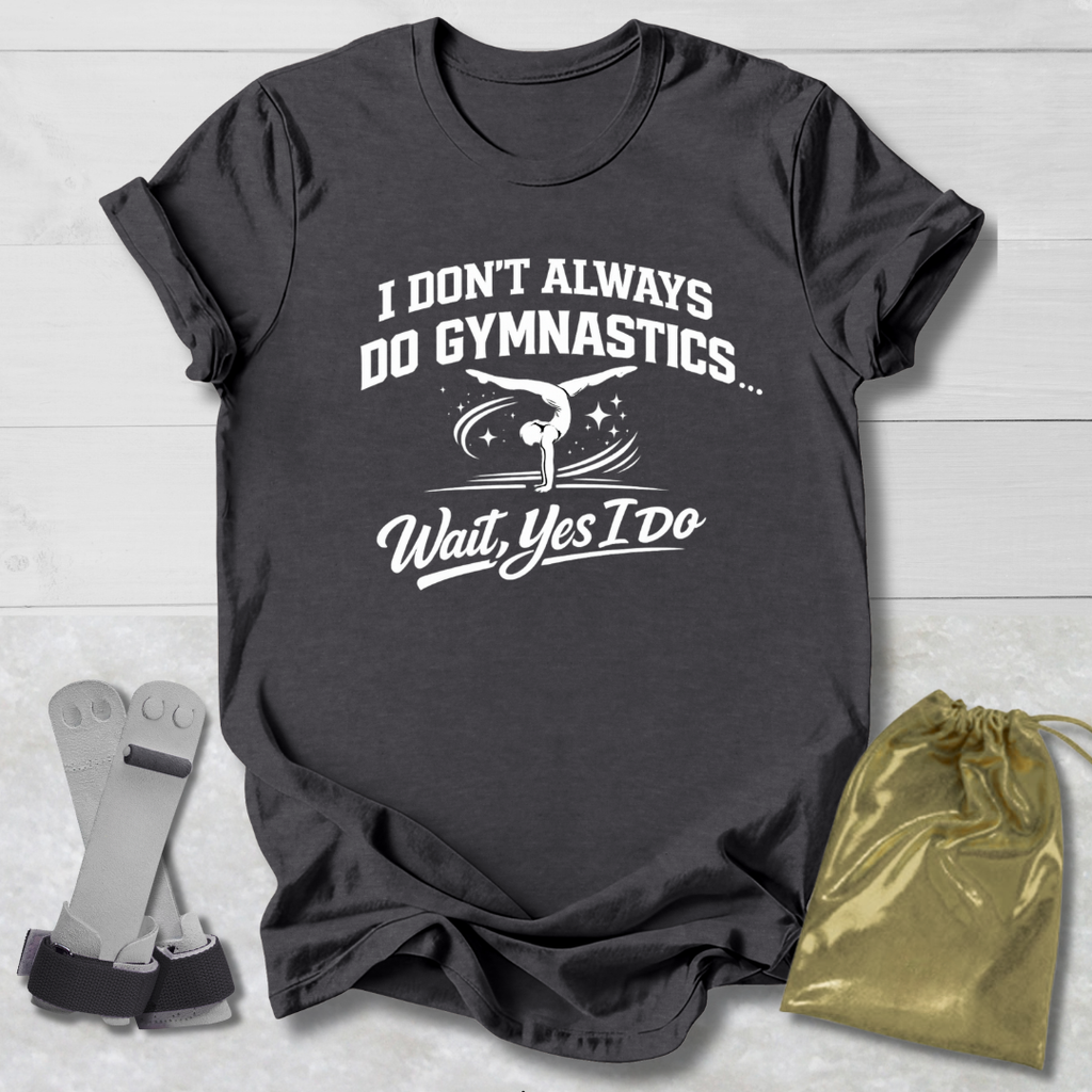 Gray t-shirt with white I don't always do gymnastics . . . wait, yes I do text and graphics on a light wooden surface, accompanied by gray socks and a gold drawstring bag.