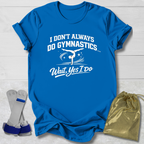 Blue t-shirt with white I don't always do gymnastics . . . wait, yes I do text and graphics on a light wooden surface, accompanied by gray socks and a gold drawstring bag.