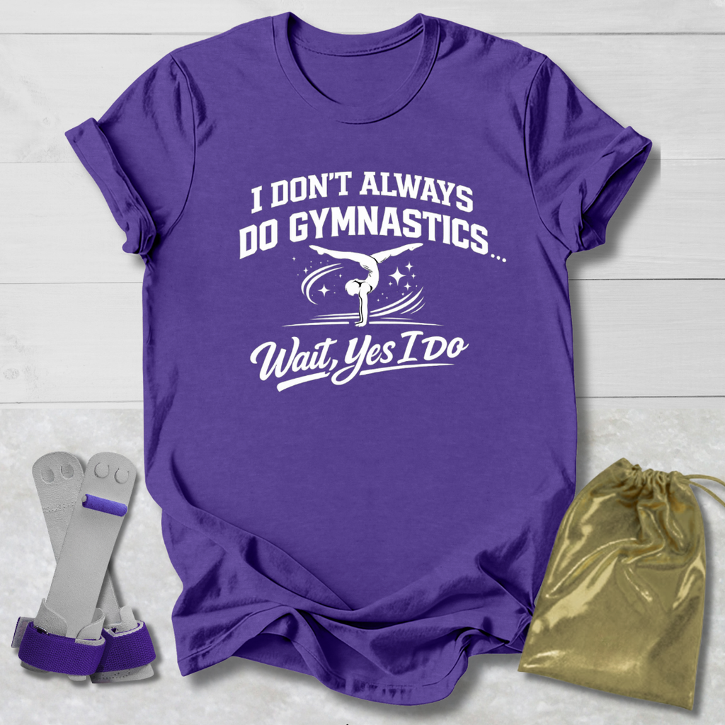 Purple t-shirt with white I don't always do gymnastics . . . wait, yes I do text and graphics on a light wooden surface, accompanied by gray socks and a gold drawstring bag.
