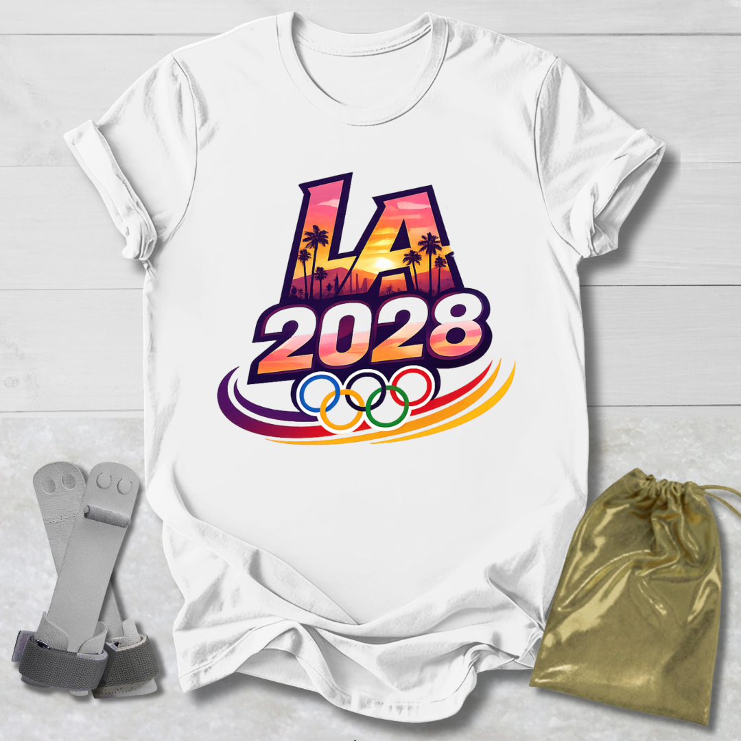 White t-shirt with 'LA 2028' Olympic design on a light wooden surface with socks and a drawstring bag.