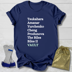 Navy blue t-shirt with  gymnast vault skills white text on a light wooden surface with socks and a drawstring bag.