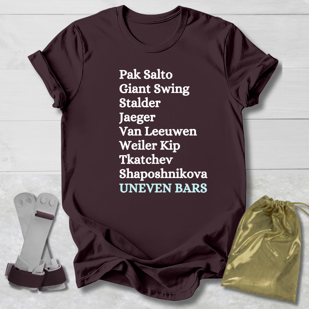 Brown t-shirt with gymnast uneven bars skills text on a light wooden surface with socks and a drawstring bag.