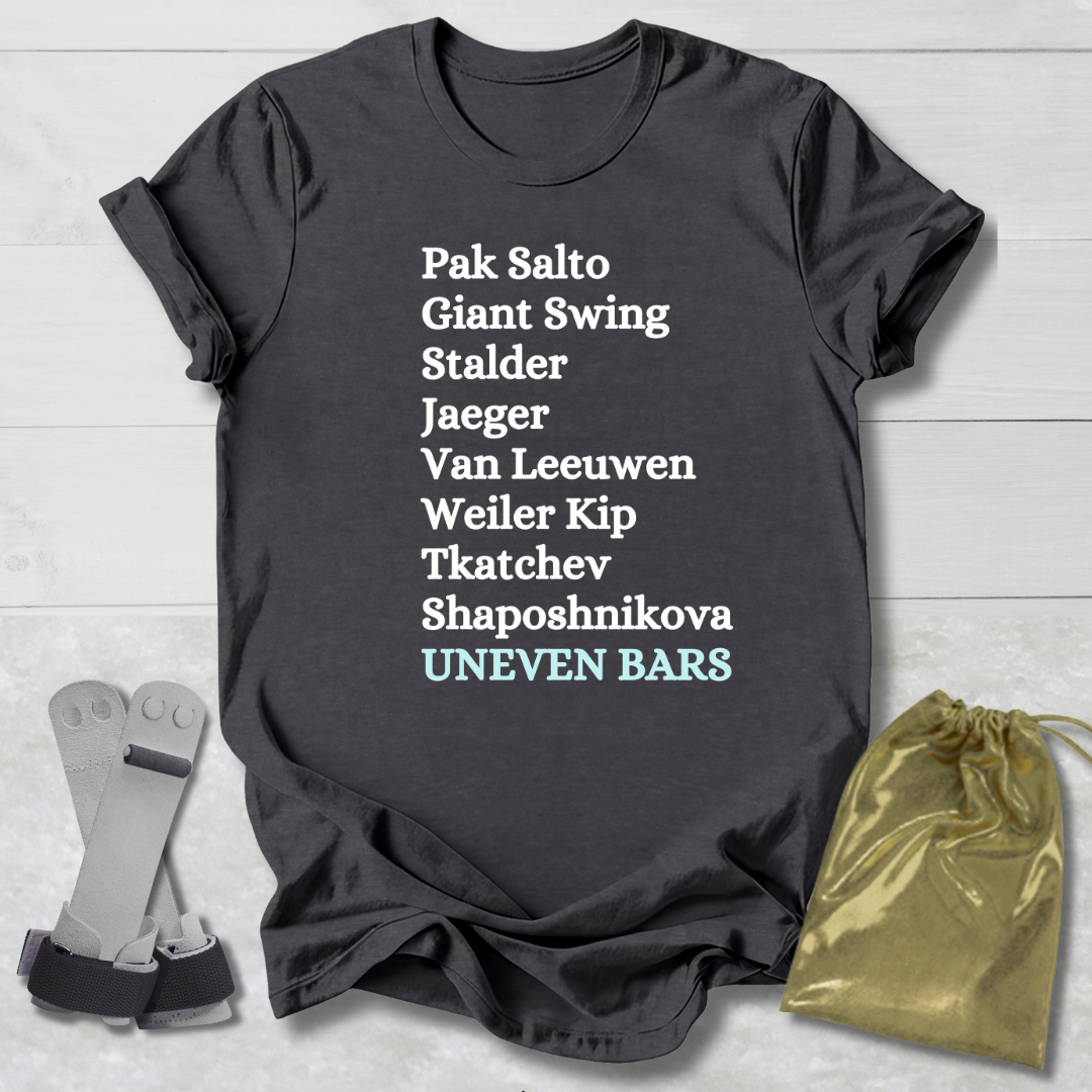 Dark gray t-shirt with gymnast uneven bars skills text on a light wooden surface with socks and a drawstring bag.