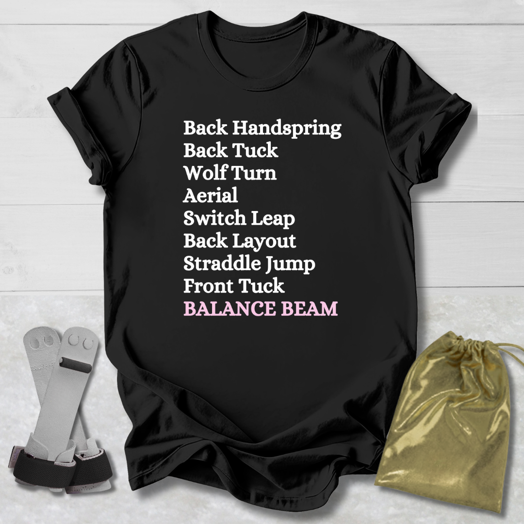 Black t-shirt with gymnast balance beam  moves text on a wooden surface with socks and a drawstring bag.