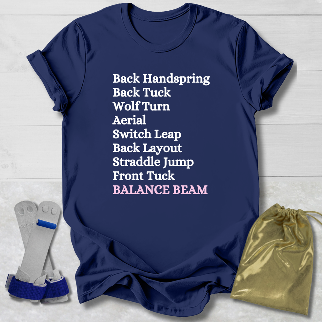Navy blue t-shirt with gymnast balance beam  moves text on a light wooden surface with socks and a drawstring bag.