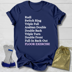 Navy blue t-shirt with white  gymnast floor exercise skills text on a light wooden surface, accompanied by socks and a drawstring bag.