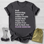 Dark gray t-shirt with floor exercise skills, socks, and drawstring bag on a light wooden surface