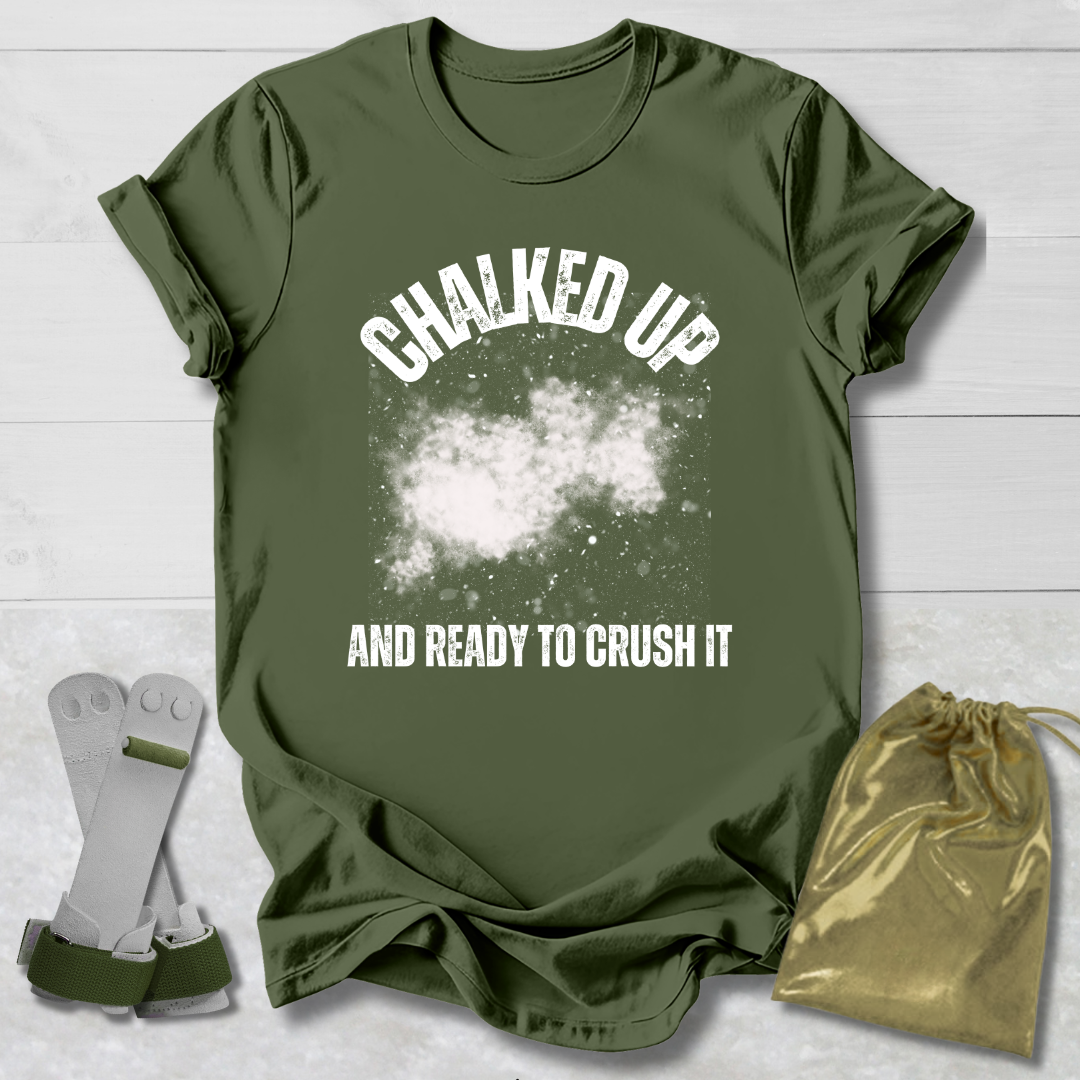 Green t-shirt with 'Chalked Up and Ready to Crush It' text, socks, and drawstring bag on a light wooden surface.