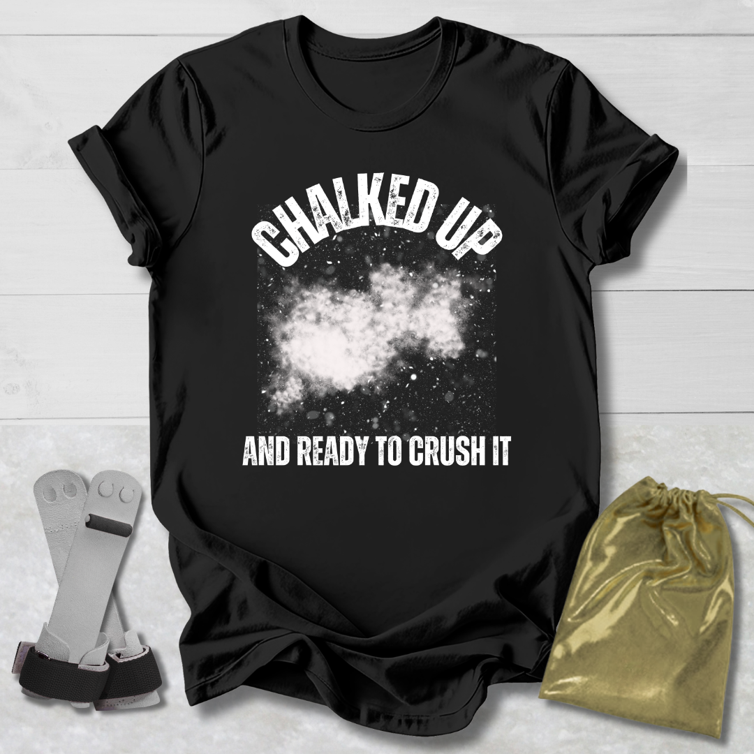Black t-shirt with 'Chalked Up and Ready to Crush It' text, socks, and drawstring bag on a light wooden surface.