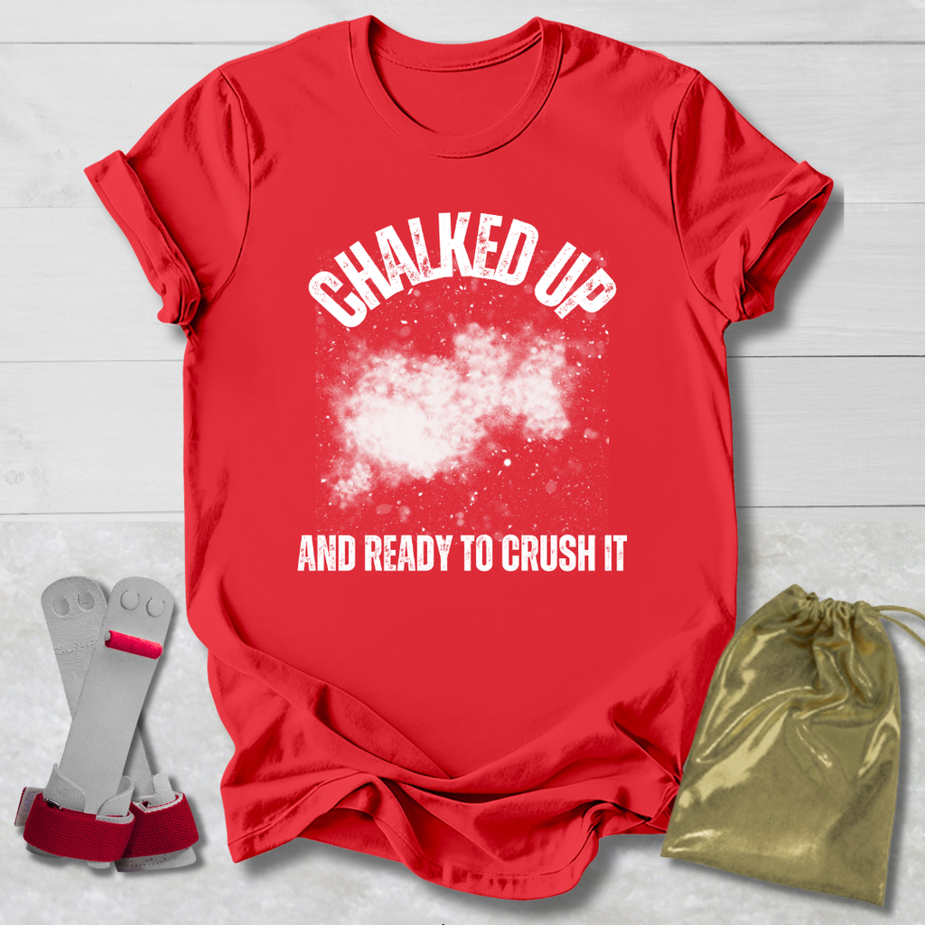 Red t-shirt with 'Chalked Up and Ready to Crush It' text, socks, and drawstring bag on a light wooden surface.