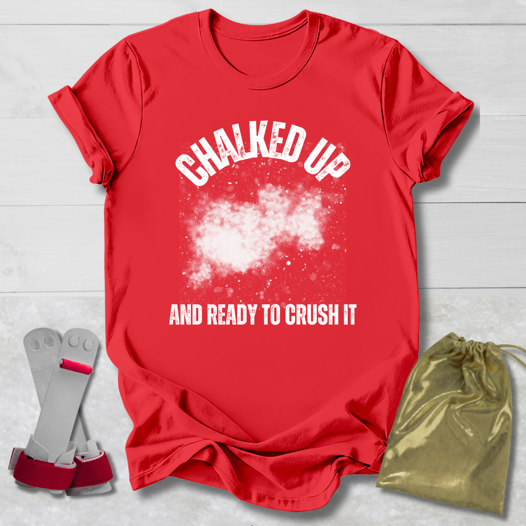 Red t-shirt with 'Chalked Up and Ready to Crush It' text, socks, and drawstring bag on a light wooden surface.