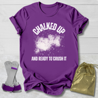 Purple t-shirt with 'Chalked Up and Ready to Crush It' text, socks, and drawstring bag on a light wooden surface.