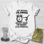 White t-shirt with black graphic and  gymnast text on a light wooden surface, with socks and a drawstring bag.