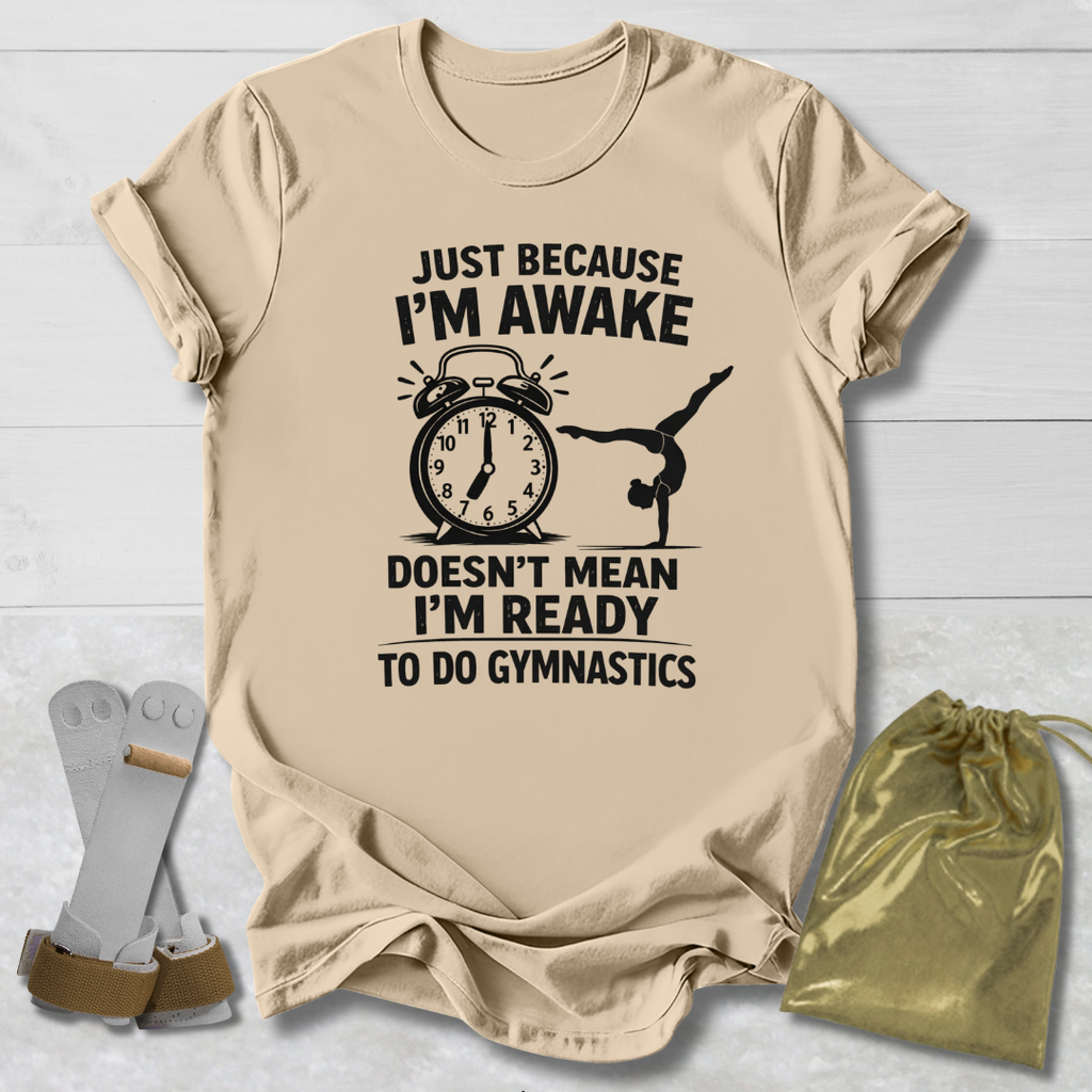 Beige t-shirt with a graphic and gymnast text on a light wooden surface, accompanied by socks and a drawstring bag.