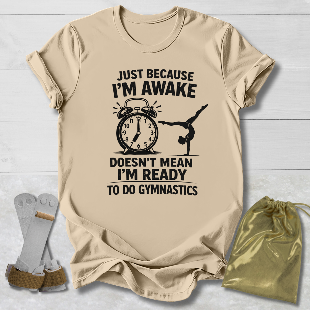Beige t-shirt with a graphic and gymnast text on a light wooden surface, accompanied by socks and a drawstring bag.