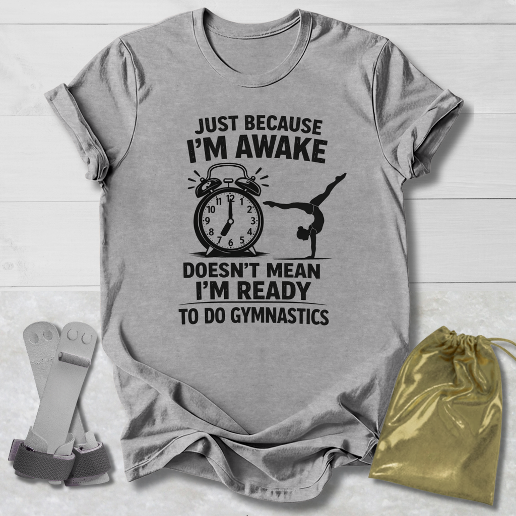 Gray t-shirt with gymnastics-themed text and graphics on a wooden surface with socks and a drawstring bag.