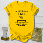 Yellow t-shirt with humorous gymnast if you didn't fall, did you even train? text design on a light wooden surface with socks and a drawstring bag.