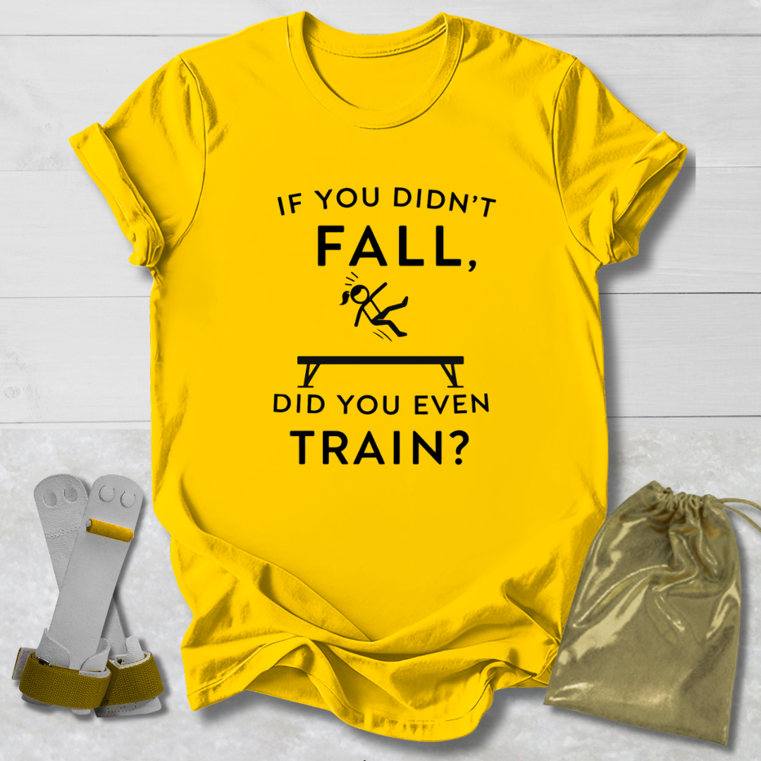 Yellow t-shirt with humorous gymnast if you didn't fall, did you even train? text design on a light wooden surface with socks and a drawstring bag.