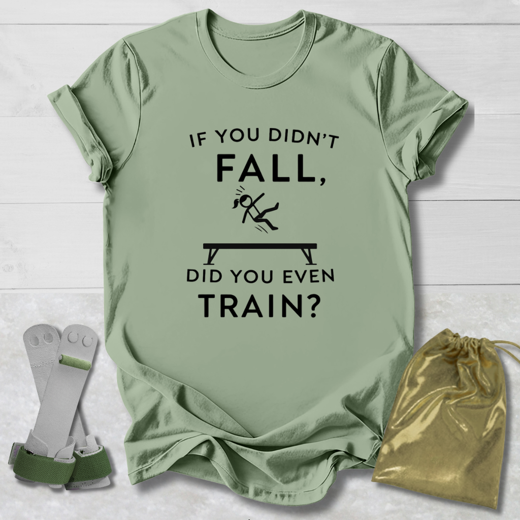 Green t-shirt with humorous gymnast if you didn't fall, did you even train? text design on a light wooden surface with socks and a drawstring bag.