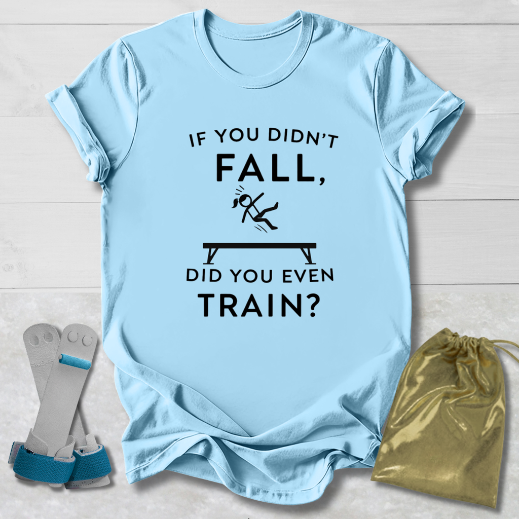 Light t-shirt with humorous gymnast if you didn't fall, did you even train? text design on a light wooden surface with socks and a drawstring bag.