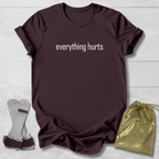 Maroon t-shirt with 'GYMNASTICS Mom' text, socks, and drawstring bag on a light wooden surface