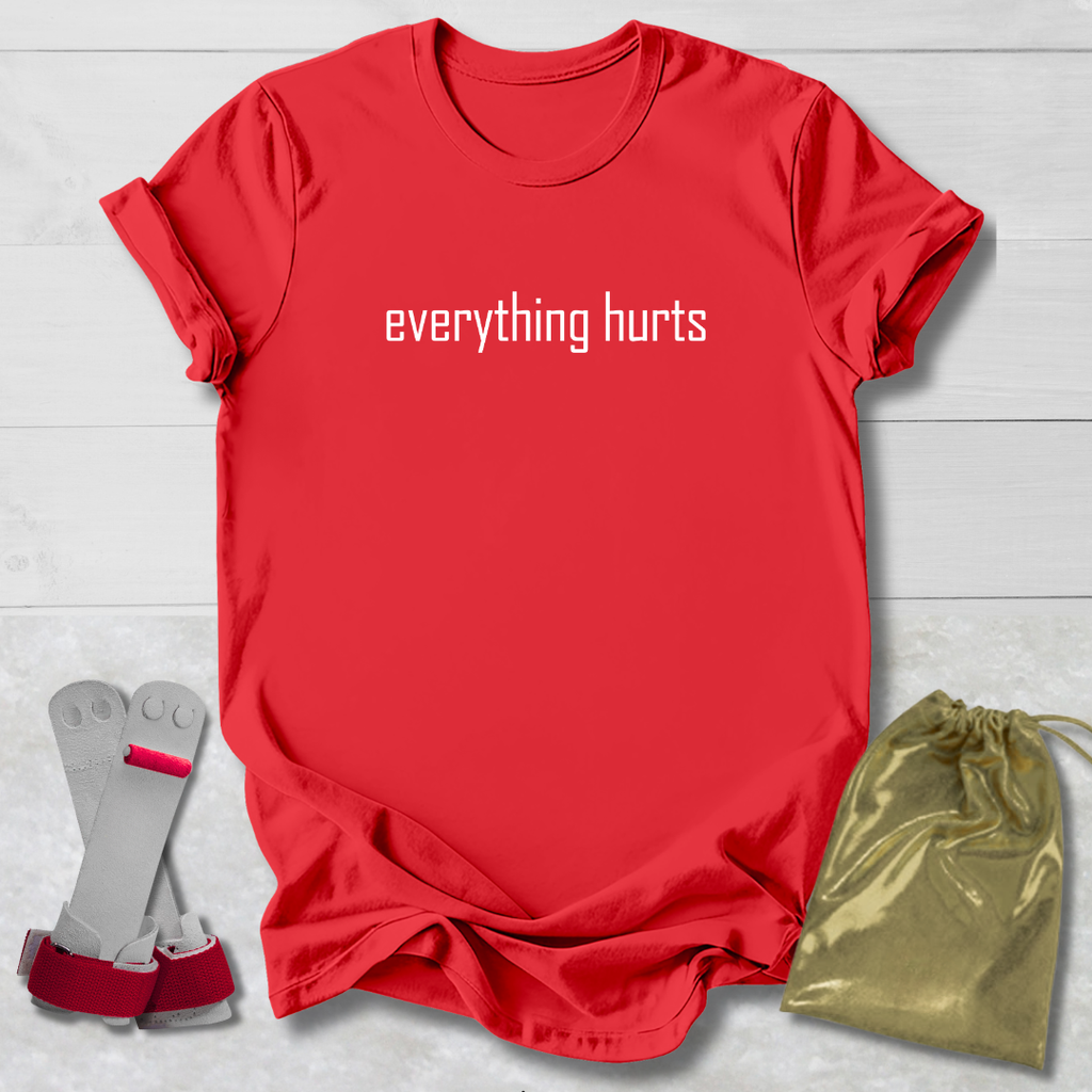 Red t-shirt with 'everything hurts' text, gray socks, and gold drawstring bag on a light wooden surface.