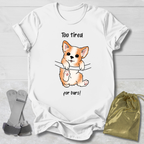 White t-shirt with a corgi graphic and  too tired for bars gymnast text, socks, and a drawstring bag on a light wooden surface.