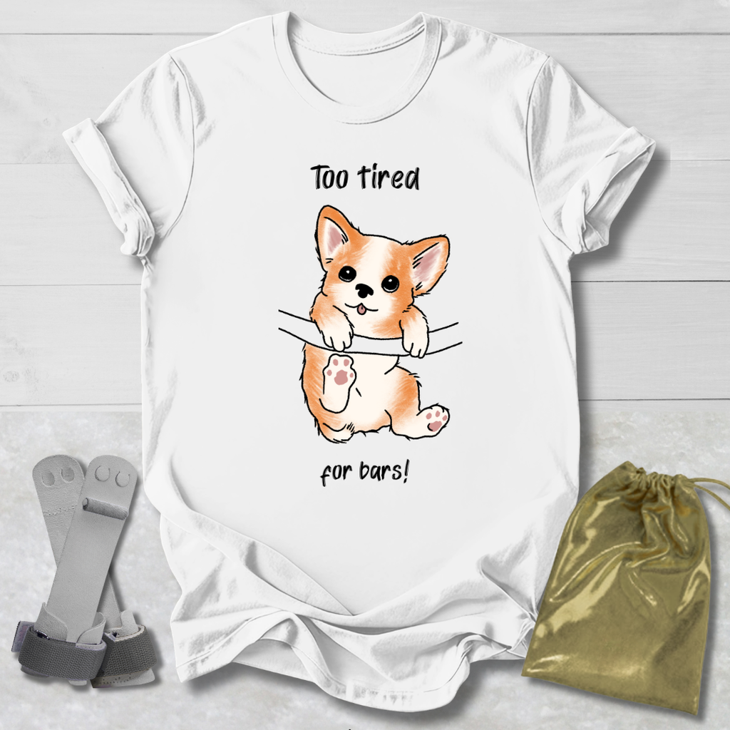 White t-shirt with a corgi graphic and  too tired for bars gymnast text, socks, and a drawstring bag on a light wooden surface.