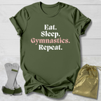 Green t-shirt with 'Eat. Sleep. Gymnastics. Repeat.' text, socks, and drawstring bag on a light wooden surface.