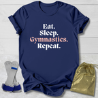 Navy blue t-shirt with 'Eat. Sleep. Gymnastics. Repeat.' text, socks, and drawstring bag on a light wooden surface.