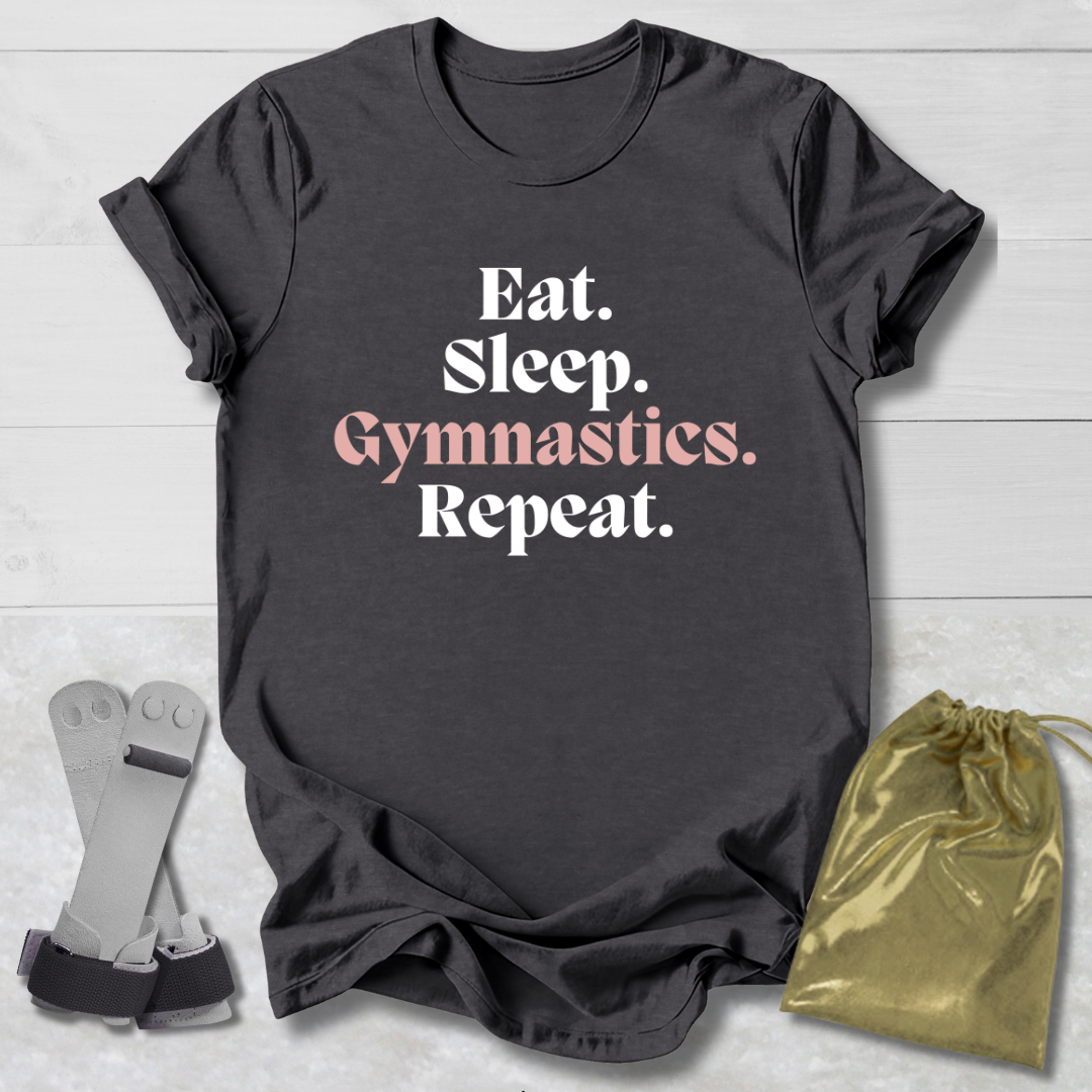 Dark gray t-shirt with 'Eat. Sleep. Gymnastics. Repeat.' text, socks, and drawstring bag on a light wooden surface.
