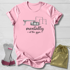 Pink t-shirt with graphic and text, socks, and drawstring bag on a light wooden surface
