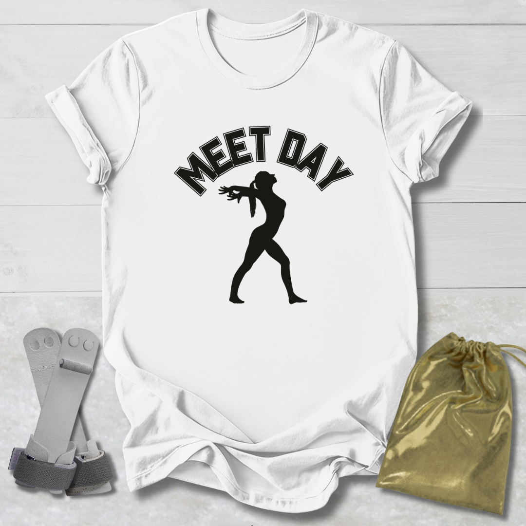 White t-shirt with black gymnast graphic and Meet Day text, socks, and drawstring bag on a light wooden surface.
