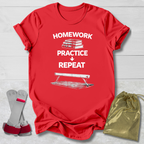 Red t-shirt with 'Homework Practice Repeat' text and graphic, socks, and drawstring bag on a light wooden surface.