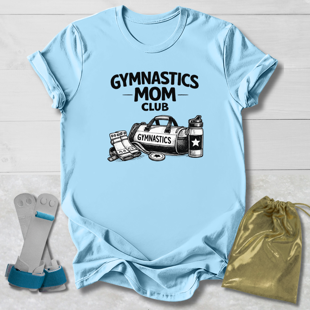 Light blue t-shirt with 'Gymnastics Mom Club' text and graphics on a wooden surface, with socks and a drawstring bag in the foreground.