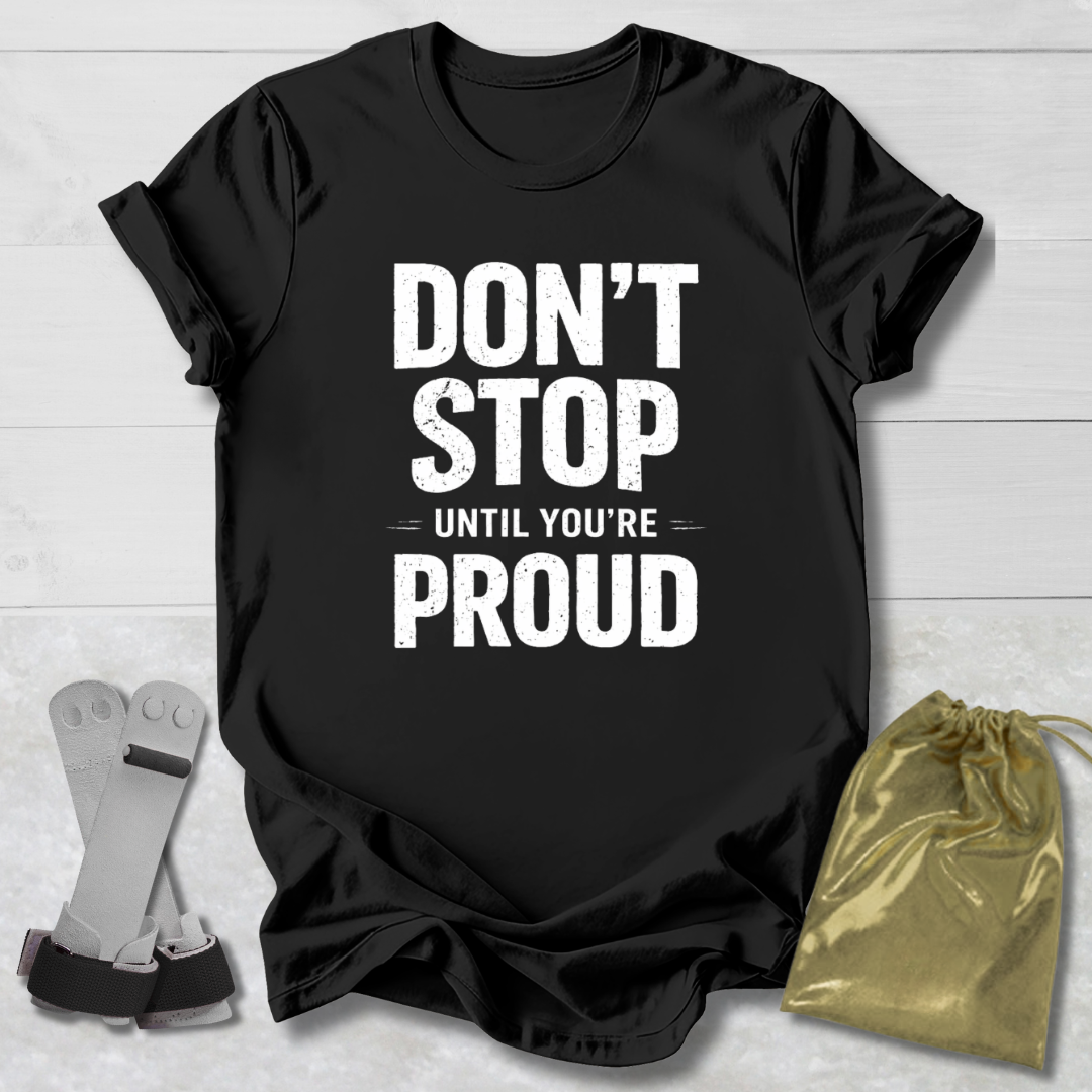 Black t-shirt with 'Don't Stop Until You're Proud' text on a light wooden surface with socks and a drawstring bag.