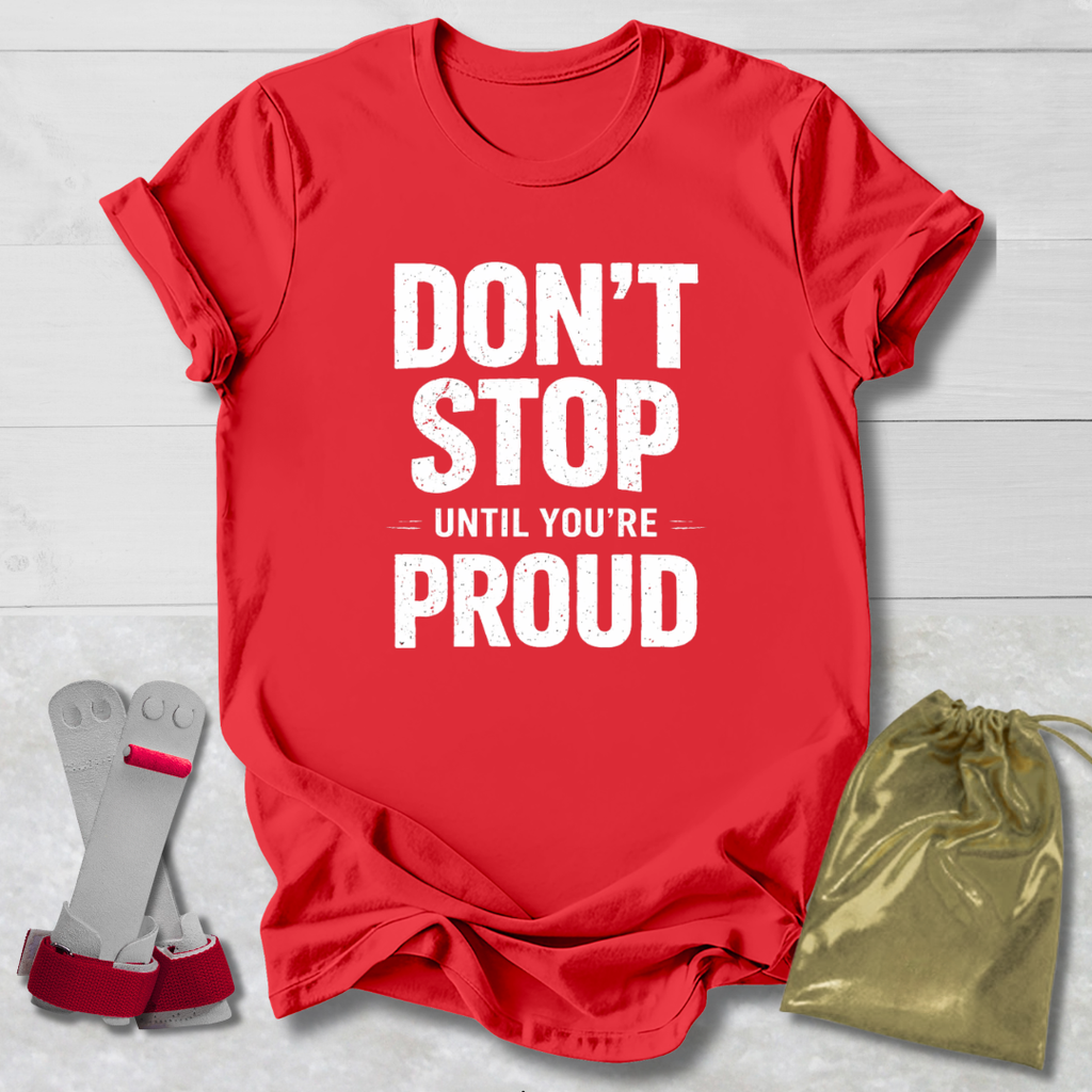 Red t-shirt with 'Don't Stop Until You're Proud' text, socks, and drawstring bag on a light wooden surface.
