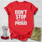 Red t-shirt with 'Don't Stop Until You're Proud' text, socks, and drawstring bag on a light wooden surface.