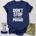 Navy blue t-shirt with 'Don't Stop Until You're Proud' text, socks, and drawstring bag on a light wooden surface.