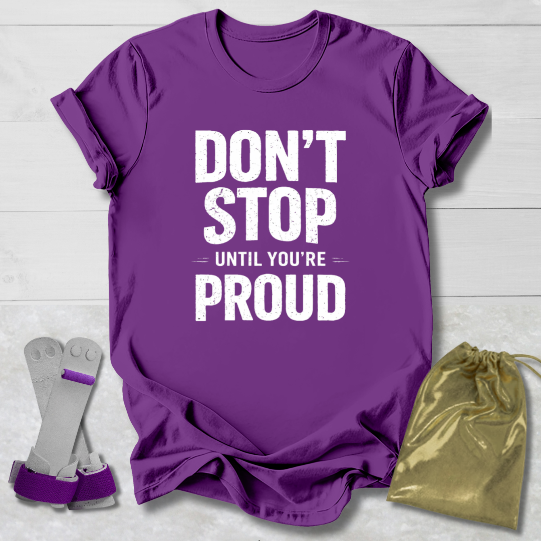 Purple t-shirt with 'Don't Stop Until You're Proud' text, socks, and drawstring bag on a light wooden surface.