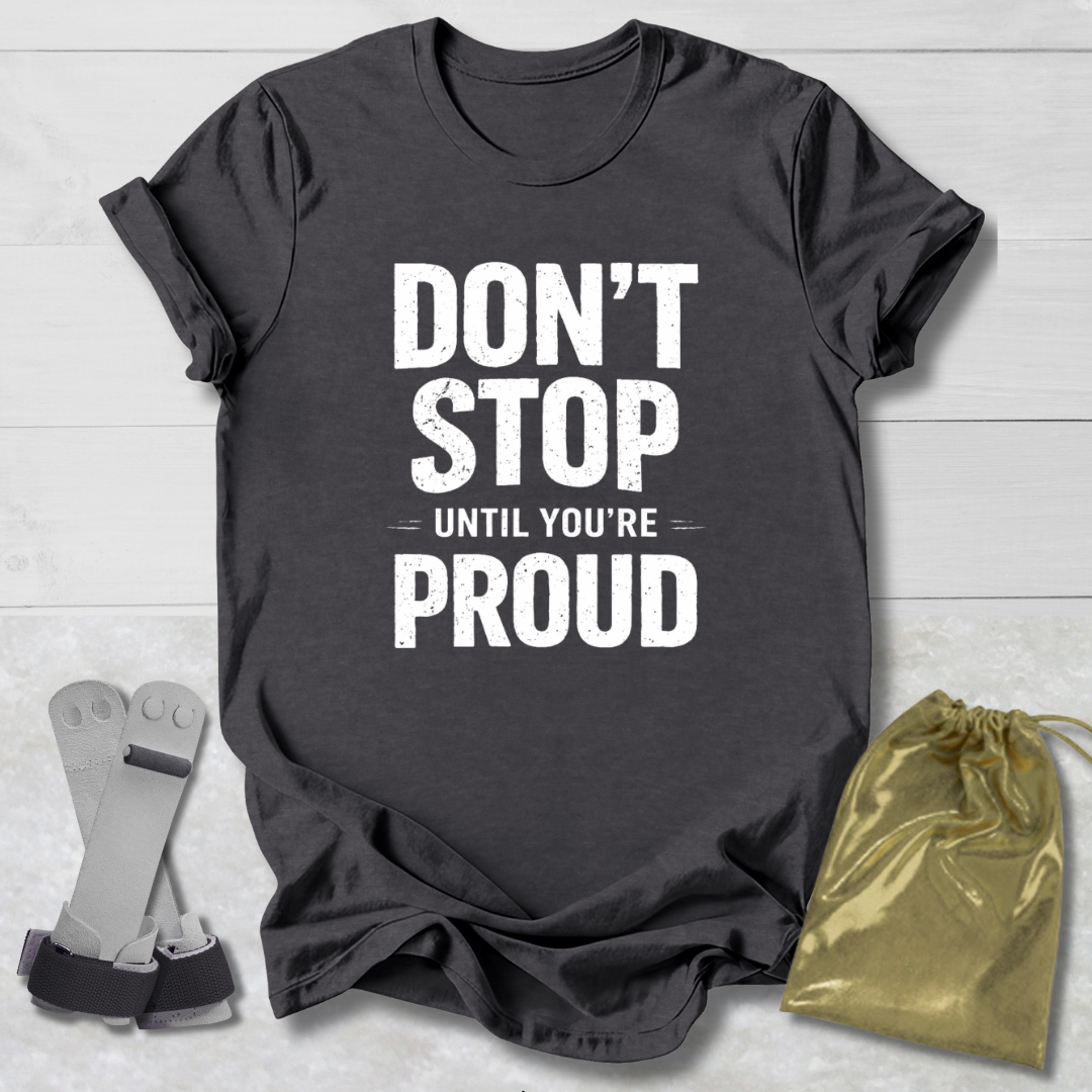 Dark gray t-shirt with 'Don't Stop Until You're Proud' text, socks, and drawstring bag on a light wooden surface.
